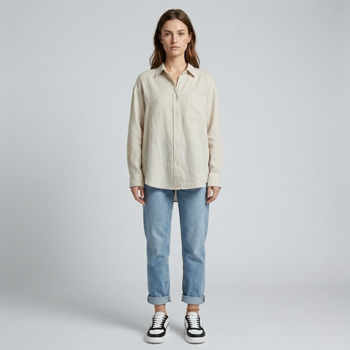Woman wearing a beige shirt and blue jeans on a plain background