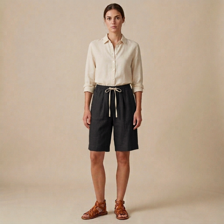 Woman wearing a beige shirt and black shorts against a beige background