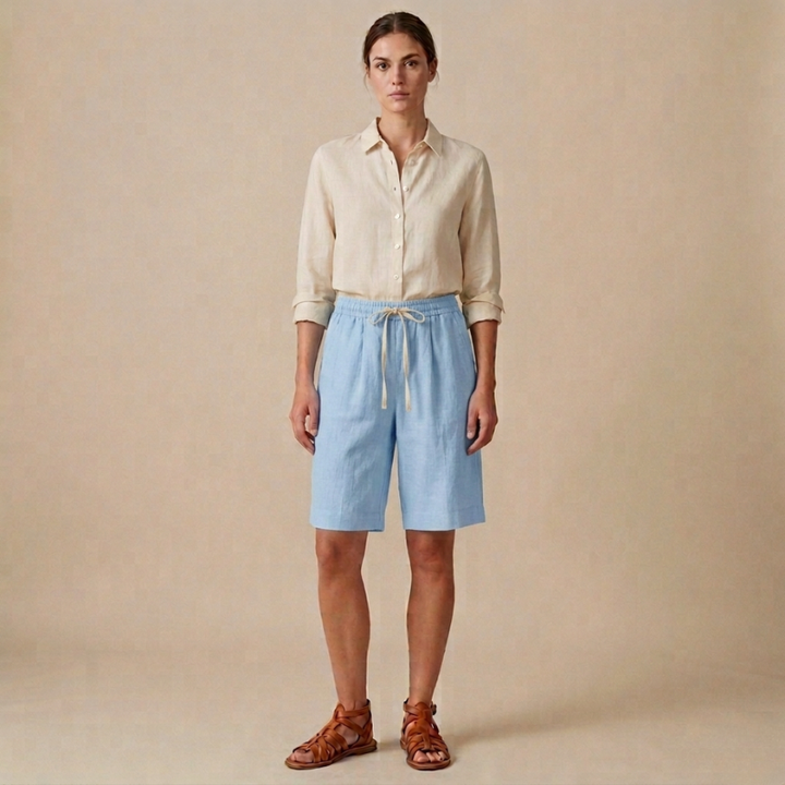 Woman wearing a beige shirt and light blue shorts against a beige background