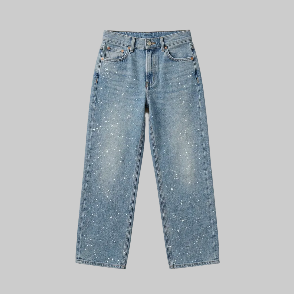 Professional studio flat lay of light wash straight-leg jeans showing the full silhouette and paint splatter pattern.