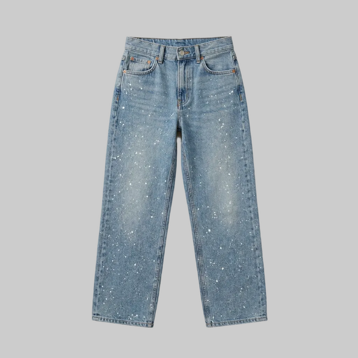 Professional studio flat lay of light wash straight-leg jeans showing the full silhouette and paint splatter pattern.