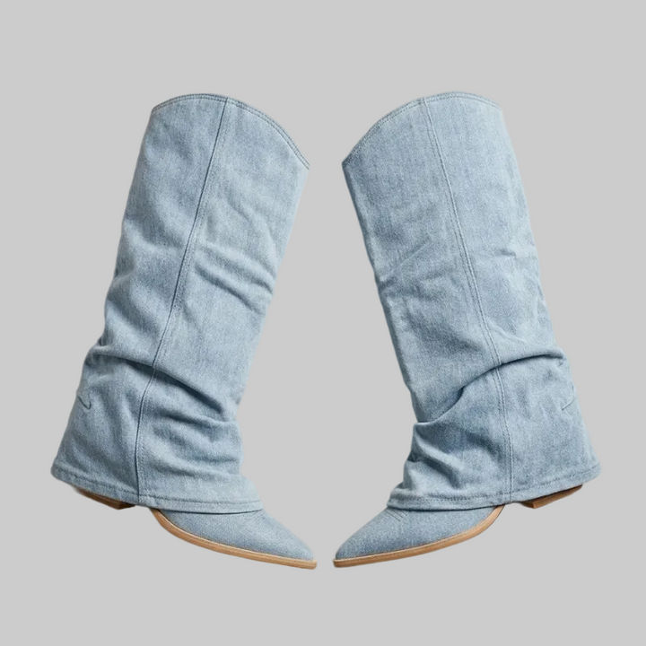 Pair of light blue denim boots on a beige background