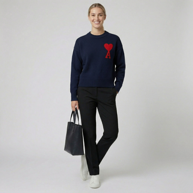Front view of a navy blue knit sweater with a red heart emblem on a female model.