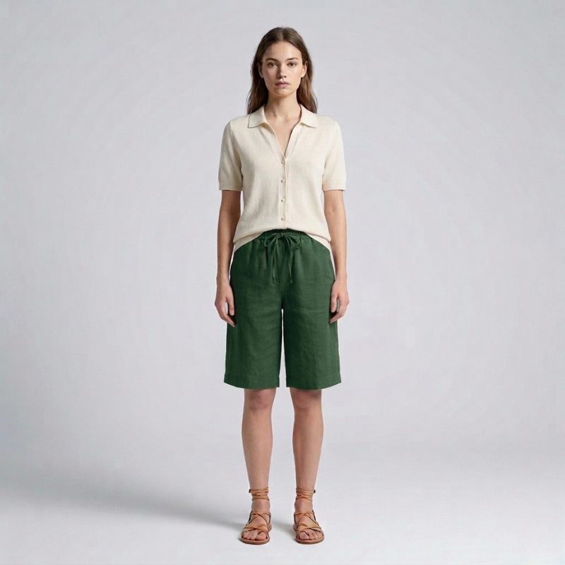 Woman wearing a beige shirt and green shorts on a plain background
