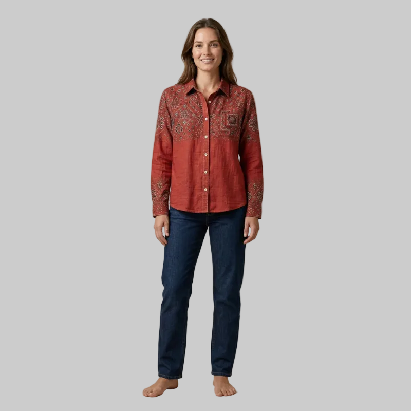 Full body shot of a model wearing an embroidered rust red long-sleeve shirt with dark blue jeans.