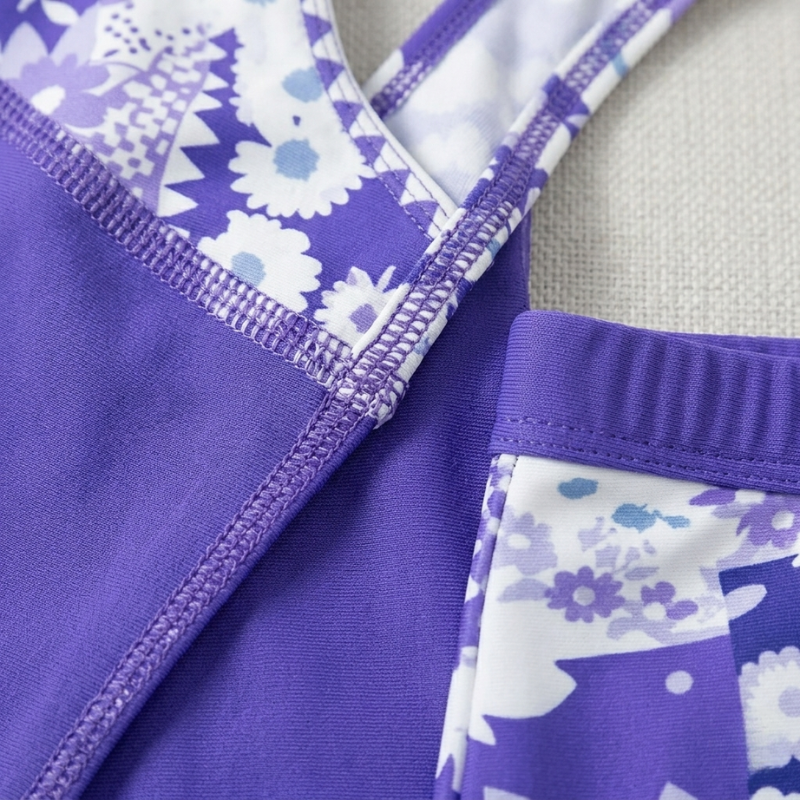 Extreme close-up showing the high-quality stitching and floral pattern detail on the purple tankini set.