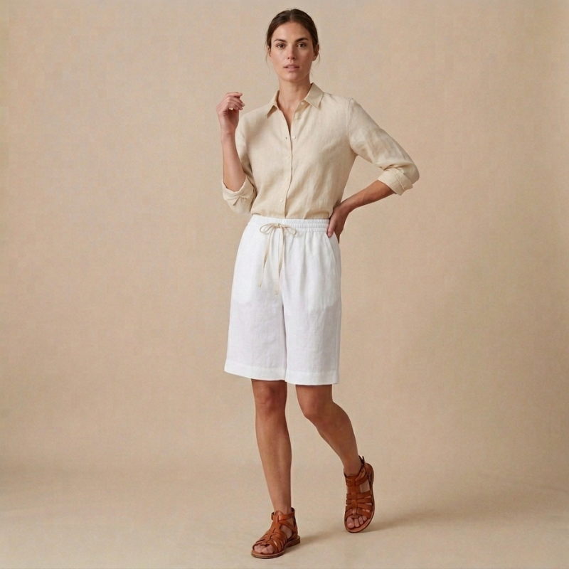 Woman wearing a beige shirt and white shorts against a beige background