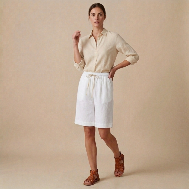 Woman wearing a beige shirt and white shorts against a beige background