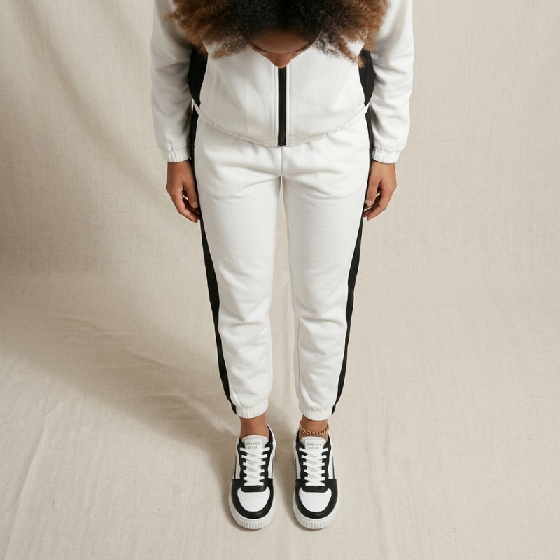 Person wearing a white tracksuit with black stripes on a beige background